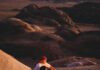Dwóch mężczyzn siedzących przy ognisku na tle pięknej pustyni Wadi Rum o zachodzie słońca.