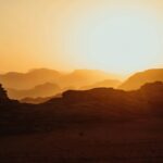 Piękny zachód słońca nad pustynią w prowincji Akaba w Jordanii, ukazujący oszałamiające sylwetki i złote odcienie.