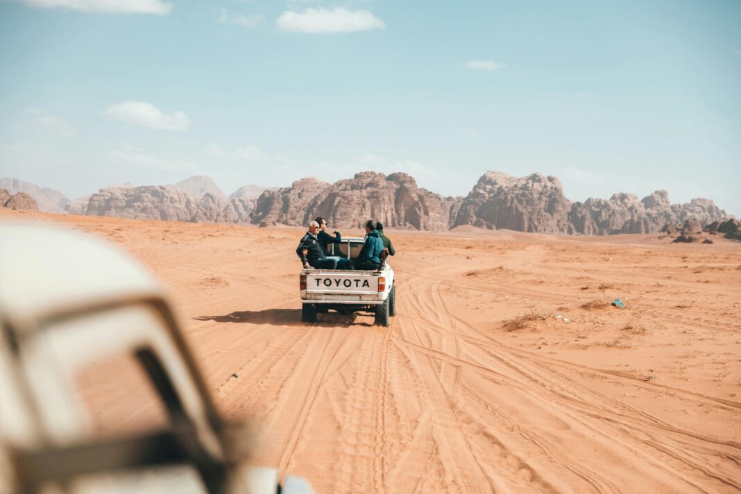 jordania Pickup z podróżnikami jeżdżącymi po pustyni Wadi Rum, ukazujący esencję przygody w Jordanii.