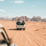 Pickup z podróżnikami jeżdżącymi po pustyni Wadi Rum, ukazujący esencję przygody w Jordanii.
