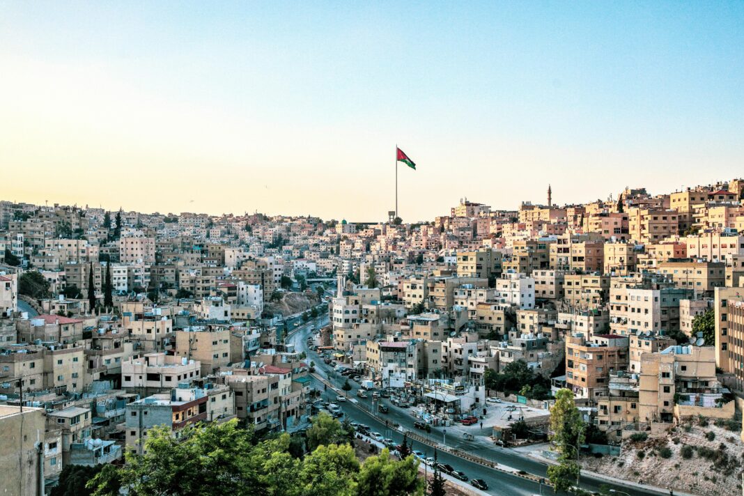 Wysoki kąt widzenia Ammanu w Jordanii z wyraźną linią horyzontu i wyraźną flagą pod czystym niebem.