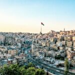 Wysoki kąt widzenia Ammanu w Jordanii z wyraźną linią horyzontu i wyraźną flagą pod czystym niebem.