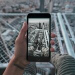 Jordańskie innowacje i startupy technologiczne Ręka trzymająca smartfon rejestrujący pejzaż Ammanu w Jordanii z perspektywy dachu.