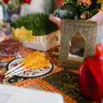 Tradycyjne nakrycie stołu Haft-sin dla Nowruz ze świątecznymi dekoracjami i symbolicznymi przedmiotami w pomieszczeniu.