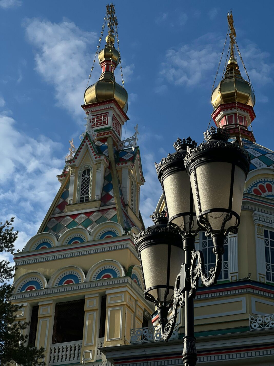 Ozdobne wieże kościelne ze złotymi kopułami i latarniami ulicznymi pod błękitnym niebem.