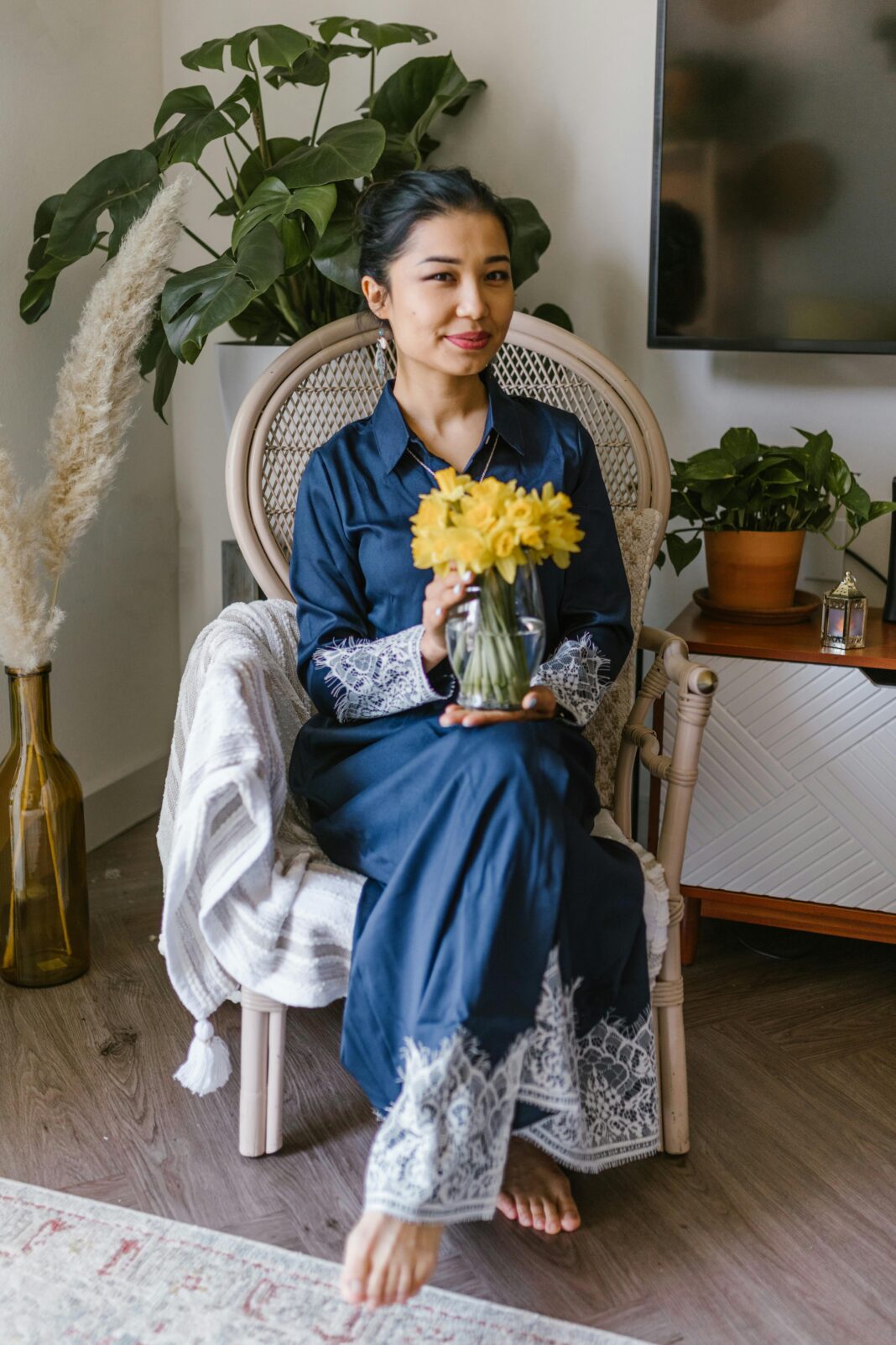 kazachstan Kobieta siedząca w pomieszczeniu z żółtymi kwiatami i świętująca Nowruz w tradycyjnej scenerii.