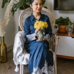 Kobieta siedząca w pomieszczeniu z żółtymi kwiatami i świętująca Nowruz w tradycyjnej scenerii.