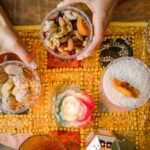 Ręce układają tradycyjne perskie przekąski dla Nowruz na udekorowanym stole przy blasku świec.