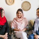 Trzy kobiety w tradycyjnych strojach dzielą się uśmiechami i poczuciem wspólnoty w pomieszczeniu podczas Nowruz.