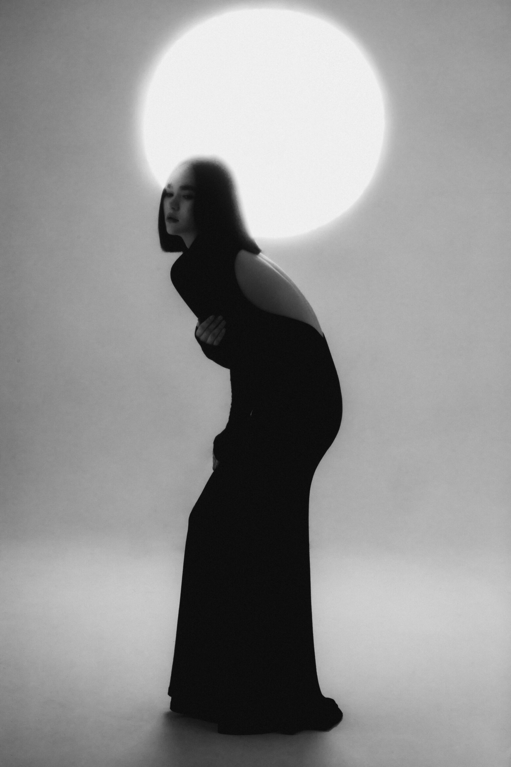 Artystyczny monochromatyczny portret kobiety w studiu z dramatycznym oświetleniem i efektem reflektora.