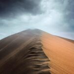 Urzekający krajobraz wydm z dramatycznym pochmurnym niebem w Altyn Emel w Kazachstanie.