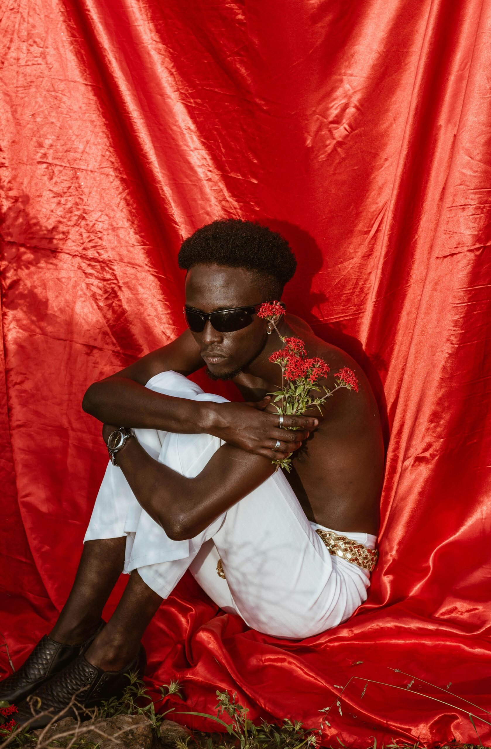 Modny mężczyzna w okularach przeciwsłonecznych emanuje stylem z żywym kontrastem czerwieni i bieli.