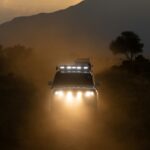 Najciekawsze regiony Kenii – przewodnik turystyczny Terenowy SUV jedzie o zachodzie słońca przez zakurzoną sawannę Tsavo w Kenii.