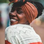 Kenia nocą – gwiazdy nad sawanną Radosna kobieta w chustce uśmiechnięta podczas sesji zdjęciowej w plenerze, promieniująca szczęściem.