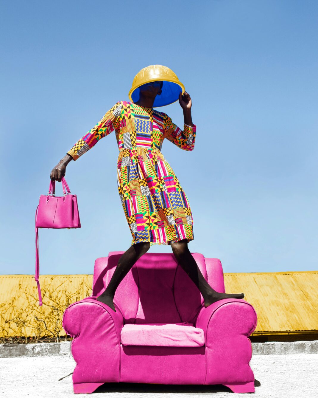 Kolorowy portret stylowej kobiety pozującej na różowym krześle na zewnątrz w Kilgoris.