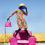 Kolorowy portret stylowej kobiety pozującej na różowym krześle na zewnątrz w Kilgoris.