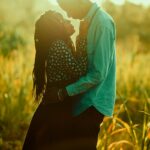 Para obejmująca się na złotym polu Kenii podczas zachodu słońca, chwytając miłość i spokój.