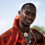 Kolorowy portret wojownika Masajów w tradycyjnym stroju, uchwycony na świeżym powietrzu w Kenii.