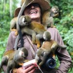 Tatacoa: Pustynia pełna kontrastów i gwiazd Uśmiechnięta osoba z małpami wiewiórkami na ramionach w amazońskiej dżungli, ukazująca interakcję z dziką przyrodą.