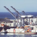 Ruchliwy port kontenerowy w Santa Marta w Kolumbii, prezentujący dźwigi i statki towarowe.