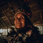 Park Narodowy Los Nevados: Wulkany i lodowce w sercu Andów Starsza tubylcza kobieta ubrana w tradycyjny nakrycie głowy z piór w amazońskiej chacie.