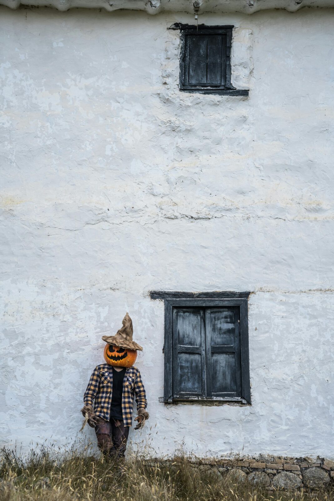 Mężczyzna z głową dyni stoi przy rustykalnej ścianie w Guasca w Kolumbii, tworząc upiorną scenę Halloween.
