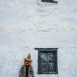 Tuluá: Miasto orchidei i tropikalnej przyrody Mężczyzna z głową dyni stoi przy rustykalnej ścianie w Guasca w Kolumbii, tworząc upiorną scenę Halloween.