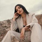 Uderzający portret kobiety w beżowym garniturze emanującej elegancją w pustynnym krajobrazie.