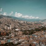 Panoramiczny widok z lotu ptaka na Medellín, ukazujący jego gęsty krajobraz miejski na tle gór.