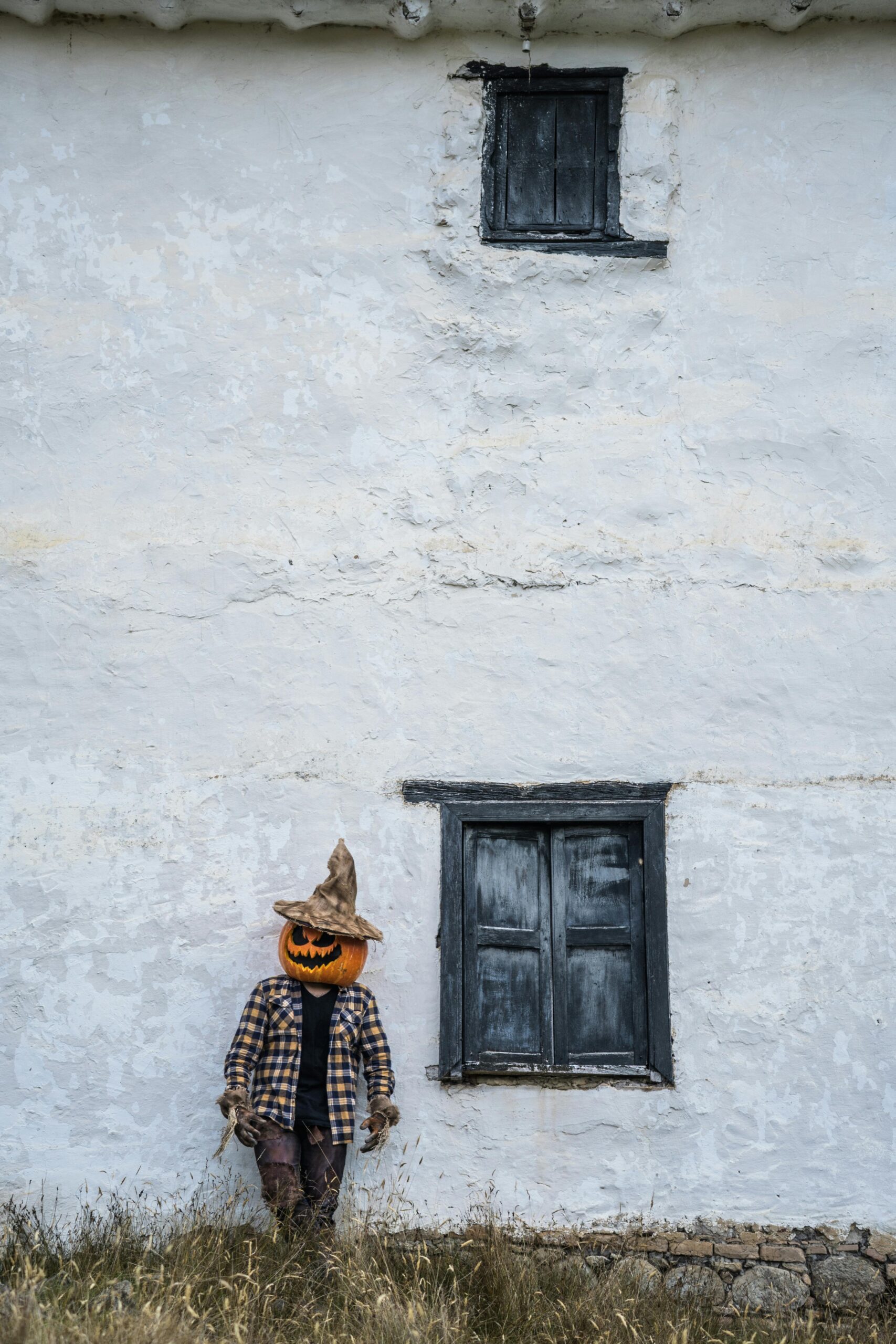 Mężczyzna z głową dyni stoi przy rustykalnej ścianie w Guasca w Kolumbii, tworząc upiorną scenę Halloween.