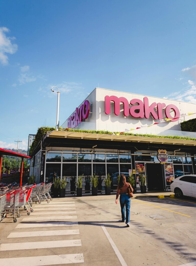 Osoba idąca w stronę sklepu Makro w Bucaramanga w Kolumbii pod czystym, błękitnym niebem.