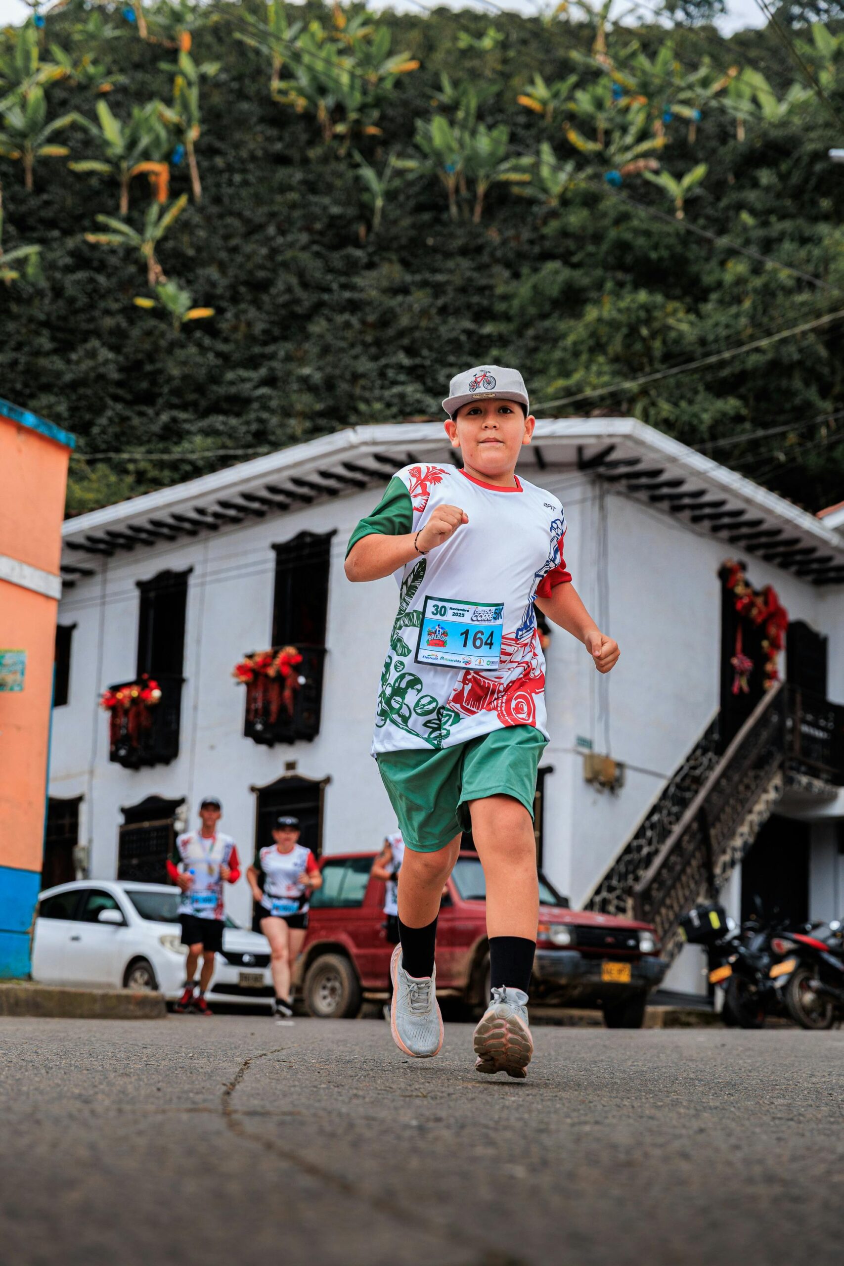 Młody chłopiec biorący udział w tętniącym życiem wyścigu miejskim z kolorowymi dekoracjami i domami.