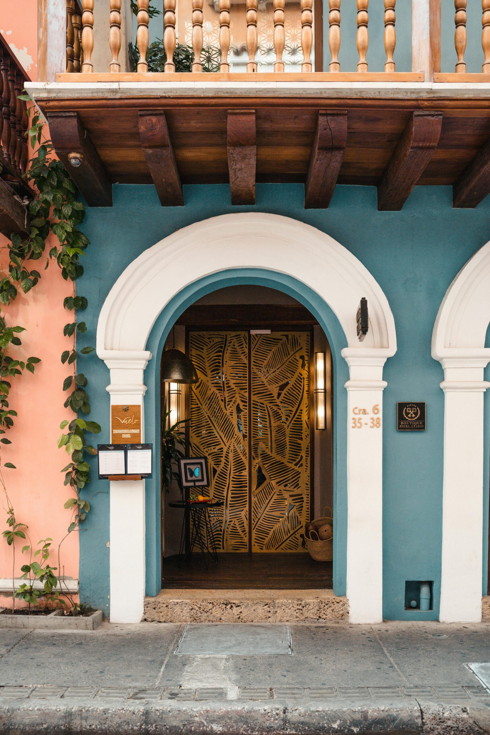 Ozdobne wejście do budynku w stylu kolonialnym z żywą fasadą i elementami dekoracyjnymi.