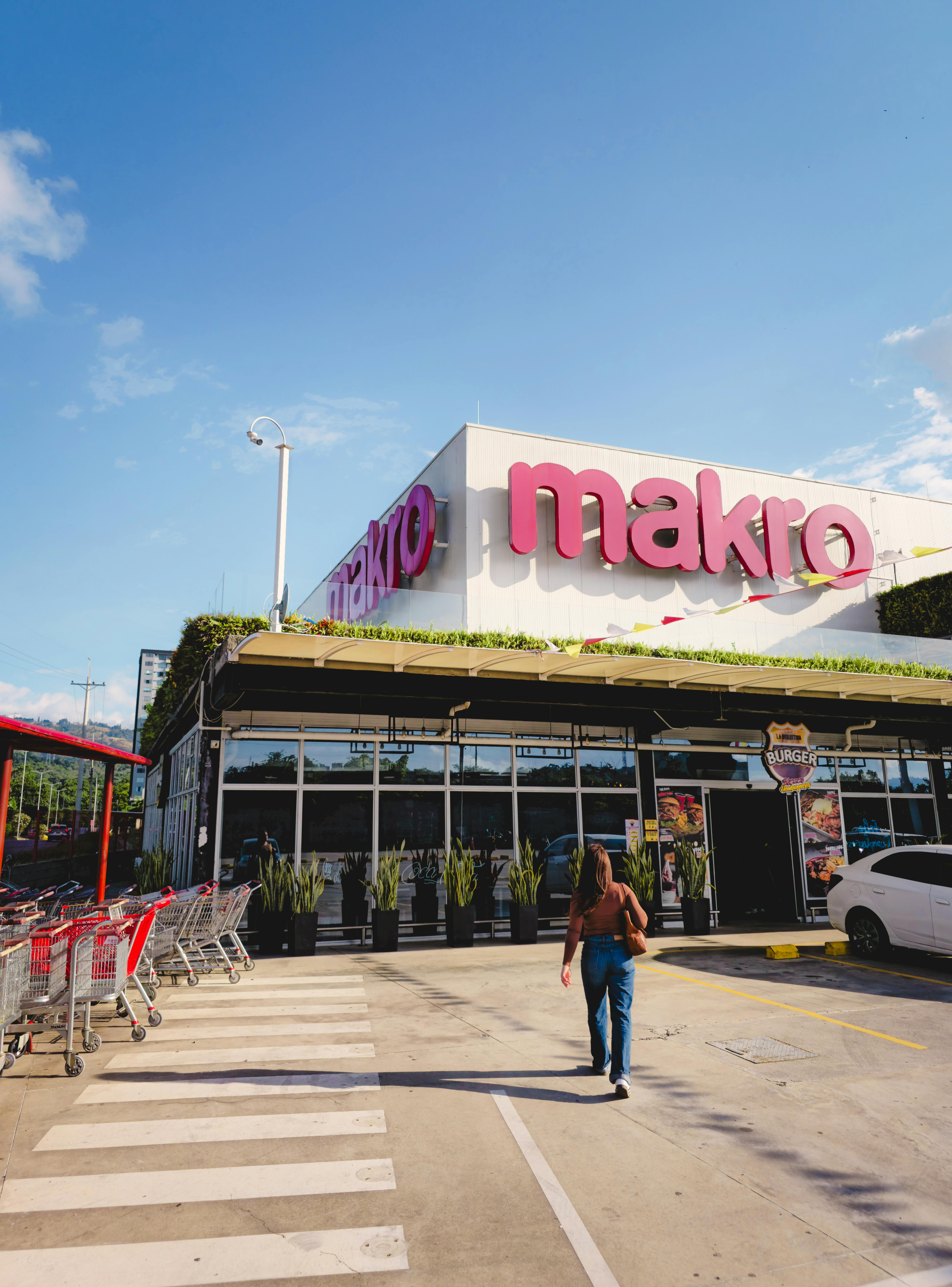 Osoba idąca w stronę sklepu Makro w Bucaramanga w Kolumbii pod czystym, błękitnym niebem.