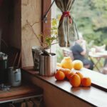 Cheonggyecheon: Oaza spokoju w centrum Seulu Ciepłe, rustykalne okno kuchenne z pomarańczami i widokiem na jadalnię na świeżym powietrzu, przywołujące przytulną, domową atmosferę.