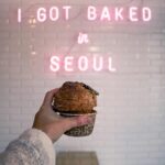 Seoul Lantern Festival: Uroczystość światła nad rzeką Cheonggyecheon Osoba trzyma babeczkę przy neonze z napisem „Upieczono mnie w Seulu”.