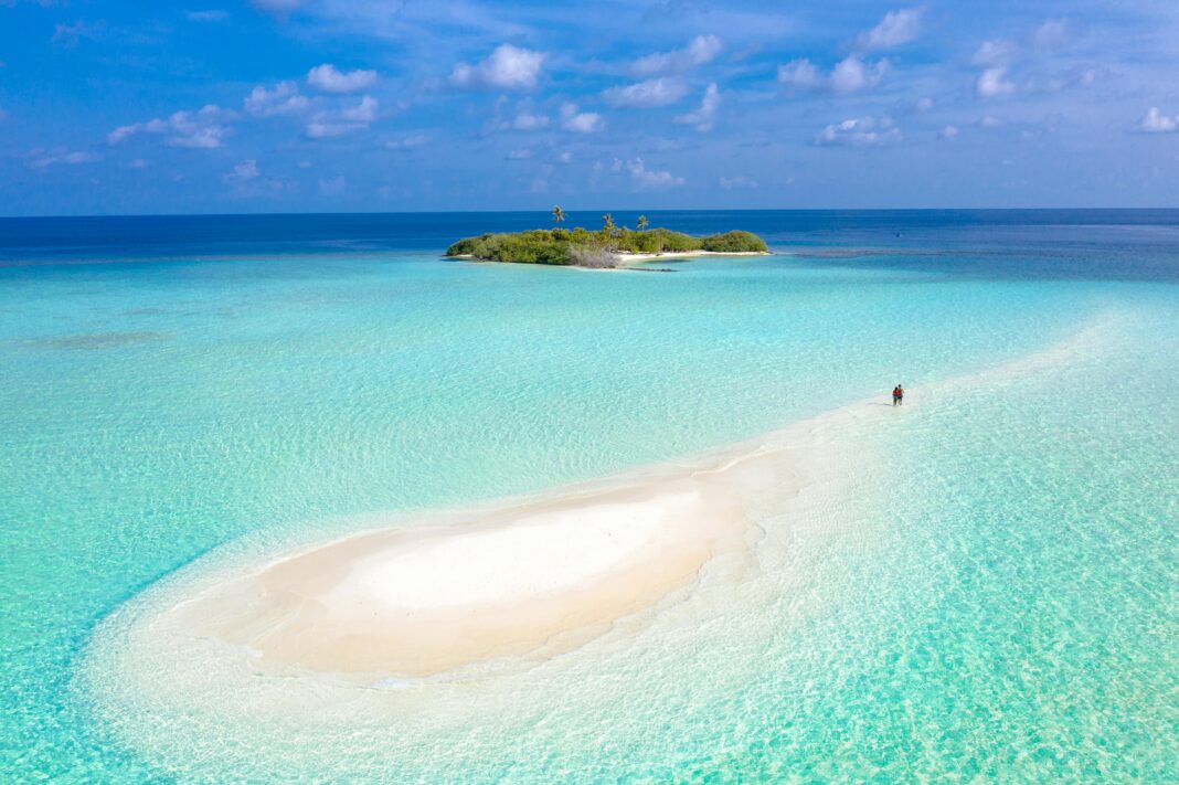 maldives Zapierający dech w piersiach widok z lotu ptaka na spokojną mierzeję prowadzącą na tropikalną wyspę otoczoną lazurowymi wodami.