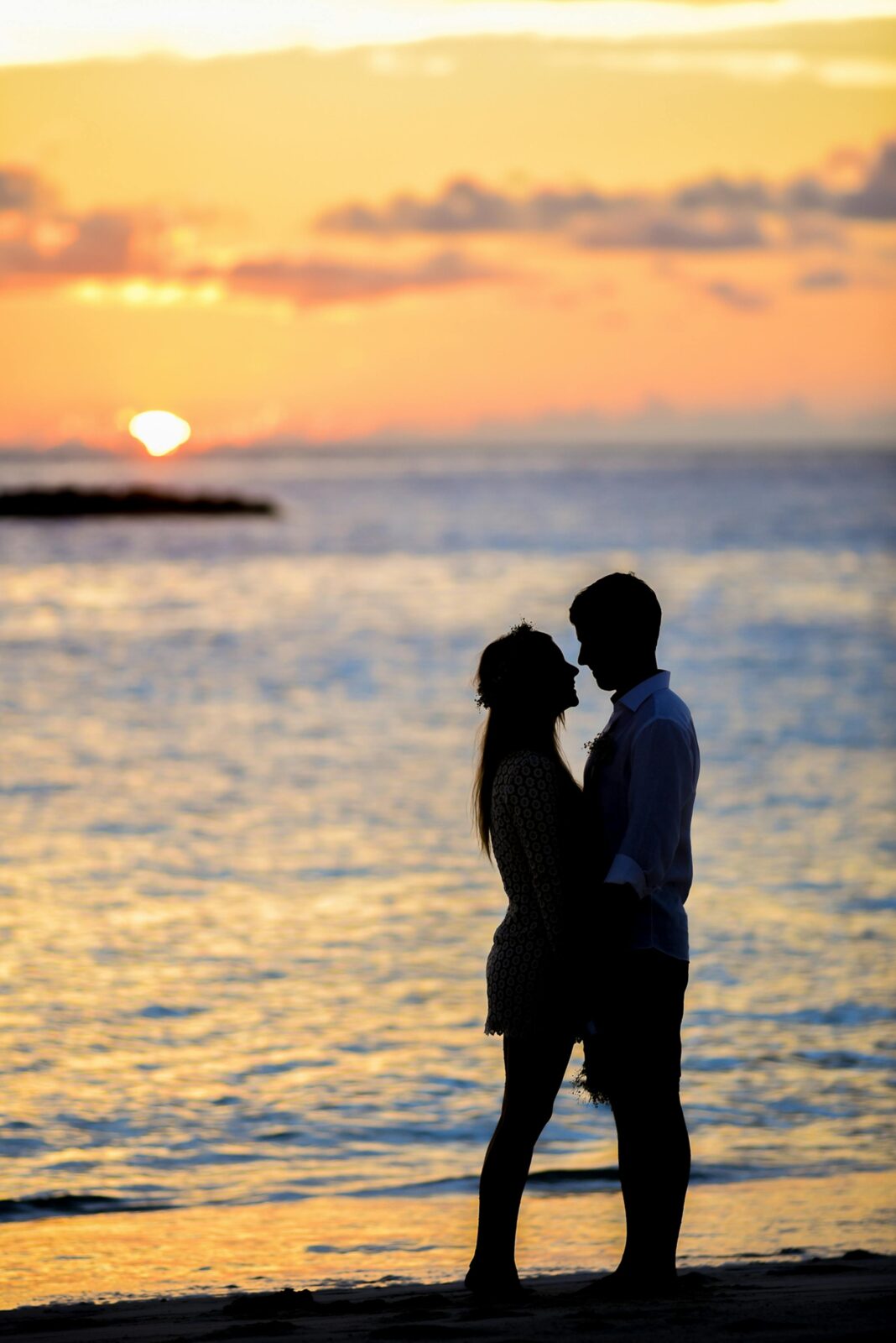 maldives Para spędzająca romantyczne chwile na plaży o zachodzie słońca, tworząc piękną sylwetkę.