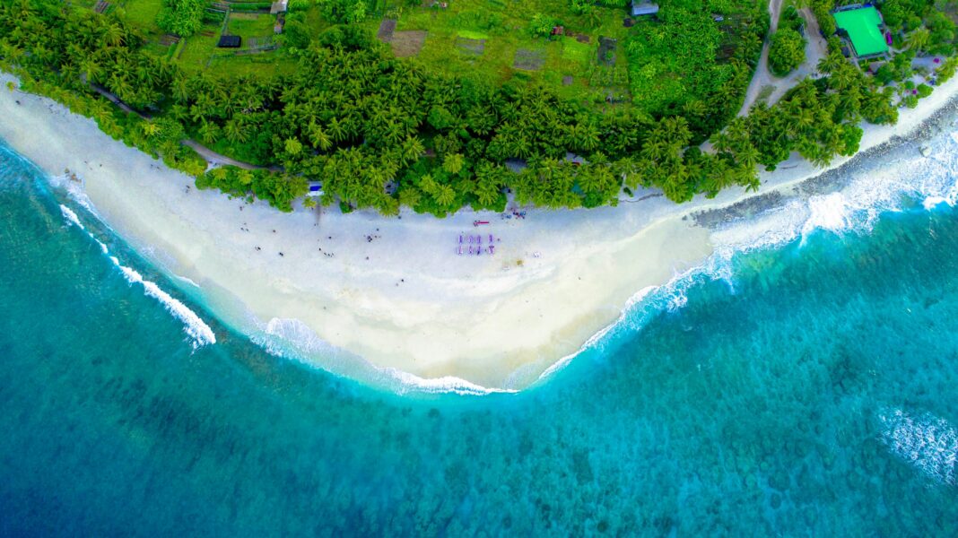 maldives Zapierający dech w piersiach widok z lotu ptaka na tropikalną plażę na wyspie z bujną zielenią i turkusowymi wodami.