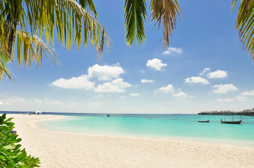 maldives Spokojna plaża z turkusową wodą, białym piaskiem i palmami pod słonecznym niebem, idealna na relaks.
