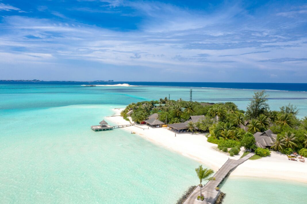 maldives Widok z lotu ptaka na idylliczny kurort na tropikalnej wyspie z turkusowymi wodami i piaszczystymi plażami.