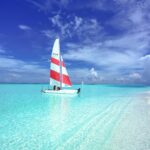 Idylliczna scena żaglówki na dziewiczych turkusowych wodach pod czystym, błękitnym niebem na Malediwach.
