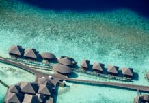 Malediwy – czy warto wybrać rejs po atolu? Oszałamiające zdjęcia lotnicze luksusowych willi nad wodą na Malediwach, ukazujące krystalicznie czyste turkusowe wody.