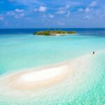 Zapierający dech w piersiach widok z lotu ptaka na spokojną mierzeję prowadzącą na tropikalną wyspę otoczoną lazurowymi wodami.