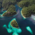 Odkryj zapierający dech w piersiach widok z lotu ptaka, przedstawiający tętniące życiem wyspy na jeziorach otoczone bujnymi lasami.