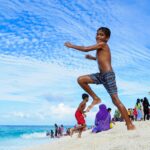 Dzieci cieszące się słonecznym dniem na plaży Fuvahmulah na Malediwach, pełne śmiechu i zabawy.