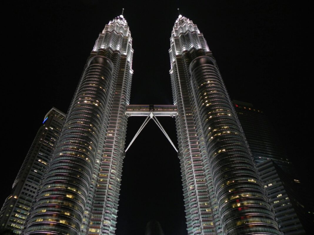 Zapierające dech w piersiach zdjęcie z niskiego kąta oświetlonych nocą Petronas Towers w Kuala Lumpur.