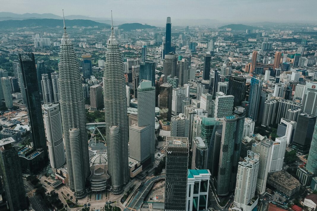 Zapierający dech w piersiach widok z lotu ptaka na panoramę Kuala Lumpur z kultowymi wieżami Petronas Towers.