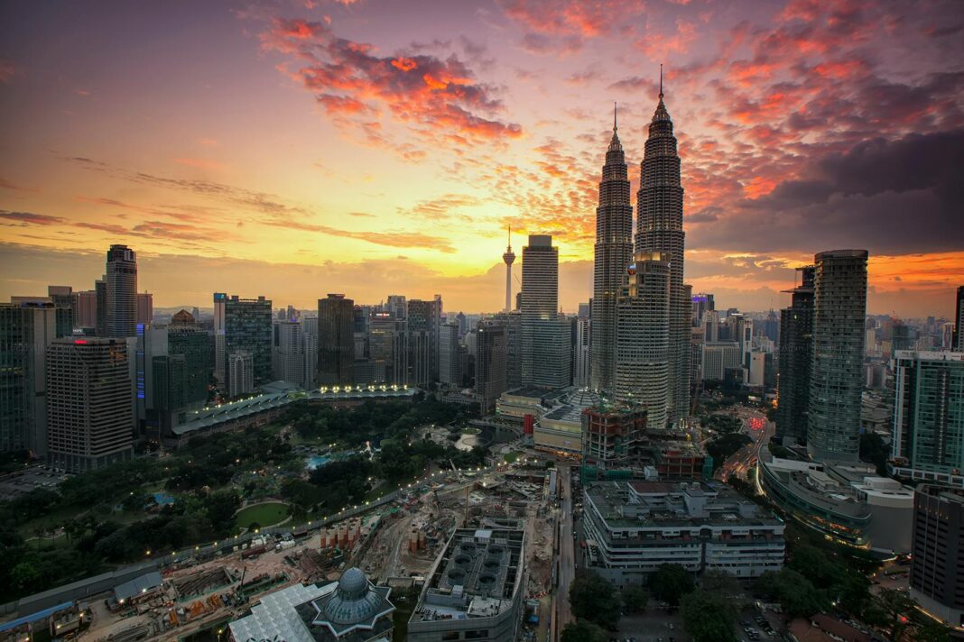 Zapierający dech w piersiach widok na panoramę Kuala Lumpur z bliźniaczymi wieżami Petronas Twin Towers o zachodzie słońca.