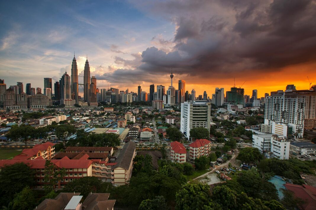 Oszałamiający widok na panoramę Kuala Lumpur z wieżami Petronas Towers o zachodzie słońca i tętniącym życiem niebem.
